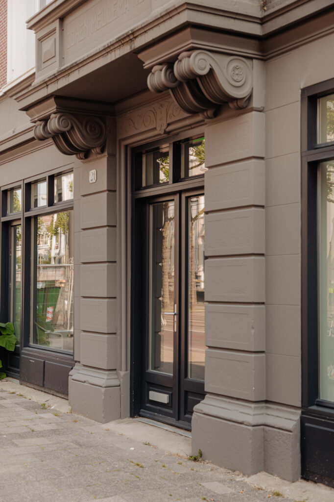 Ingang van een klassiek gebouw aan de Plantage Middenlaan met decoratieve gevel en huisnummer 21.